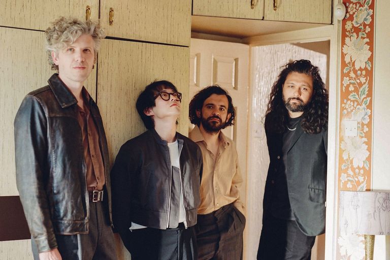 Australian alt-rock band Gang of Youths members standing in a vintage-style room in a promotional group photo.